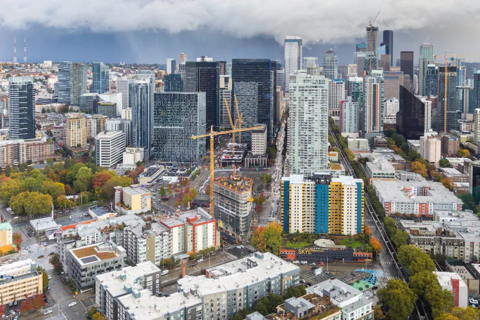 View of downtown Seattle with construction cranes and cloudy sky as seen from top of Space Needle.